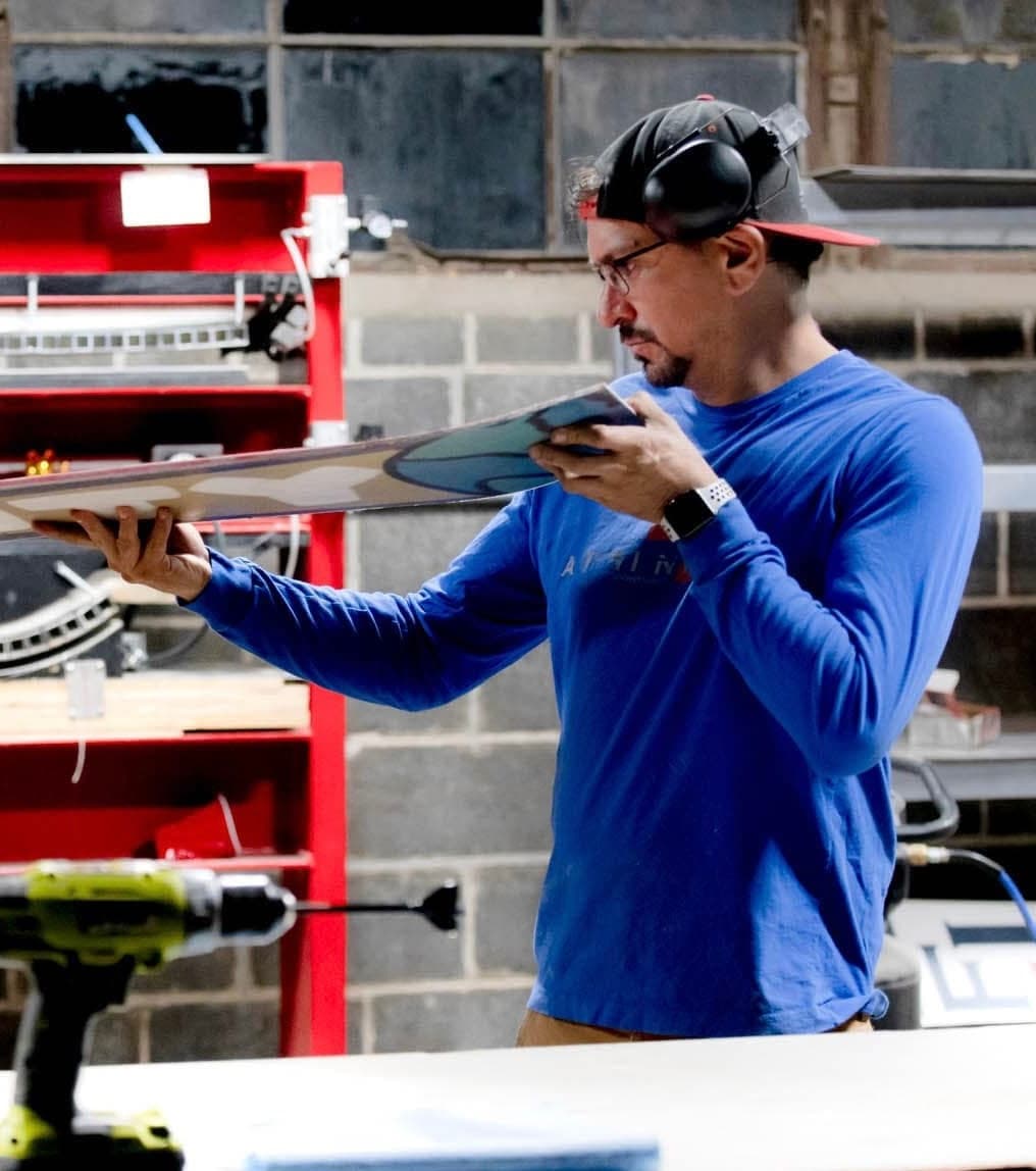 Snowboard builder examining a board in the workshop
